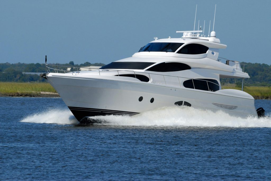 A modern luxury yacht cruising swiftly on a calm river under a clear blue sky.